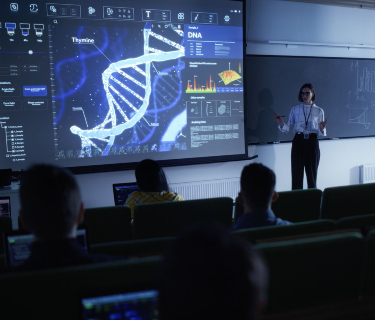 Female scientist or educator presenting a detailed DNA double helix structure labeled with nucleotide bases on a large interactive screen in a lecture hall, teaching genetics or molecular biology